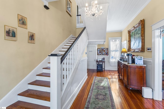 stairs with a notable chandelier, ornamental molding, and hardwood / wood-style floors