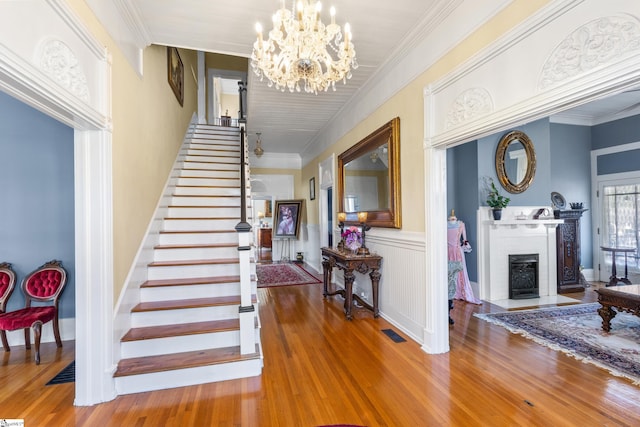 foyer with a fireplace, a notable chandelier, and hardwood / wood-style floors