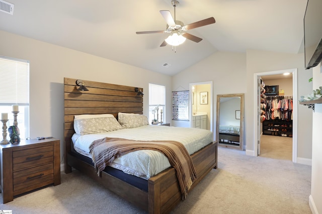 bedroom with ceiling fan, light colored carpet, ensuite bath, a spacious closet, and a closet