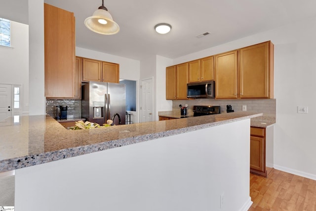 kitchen featuring decorative light fixtures, tasteful backsplash, kitchen peninsula, stainless steel appliances, and light stone countertops