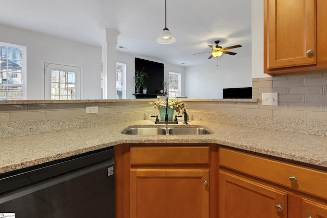 kitchen with light stone counters, black dishwasher, sink, and backsplash