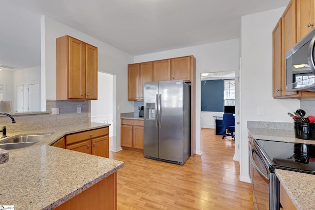 kitchen with sink, light hardwood / wood-style flooring, stainless steel appliances, and light stone countertops