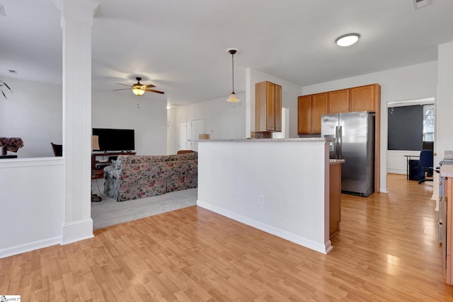 kitchen featuring hanging light fixtures, light hardwood / wood-style flooring, stainless steel fridge, ceiling fan, and decorative columns