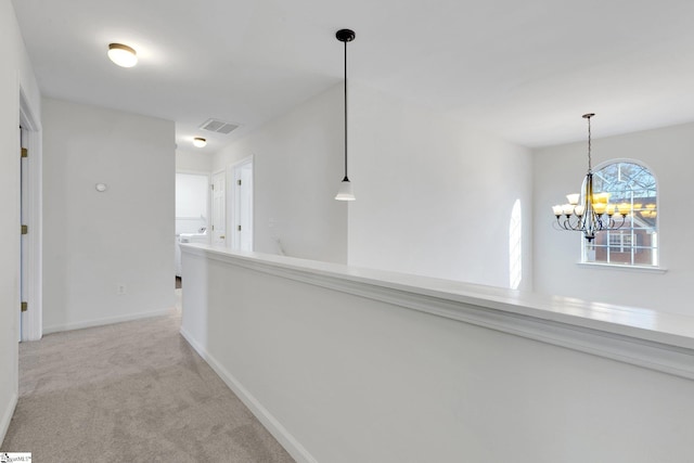 corridor featuring light colored carpet and a notable chandelier