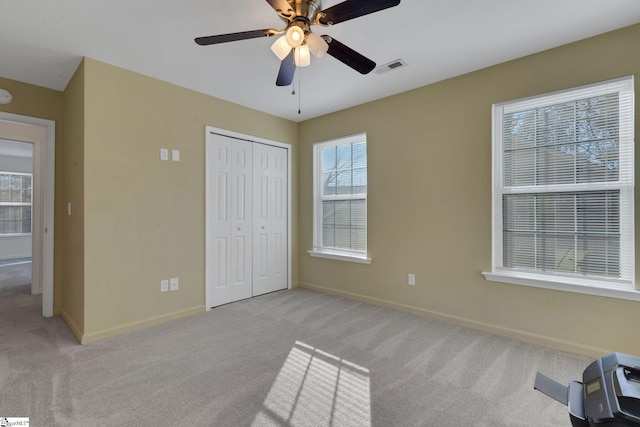 unfurnished bedroom featuring light carpet, a closet, and ceiling fan