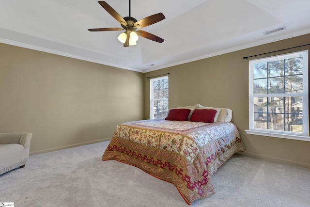 bedroom featuring crown molding, ceiling fan, a tray ceiling, and light carpet