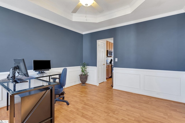 office featuring crown molding, light hardwood / wood-style floors, a raised ceiling, and ceiling fan