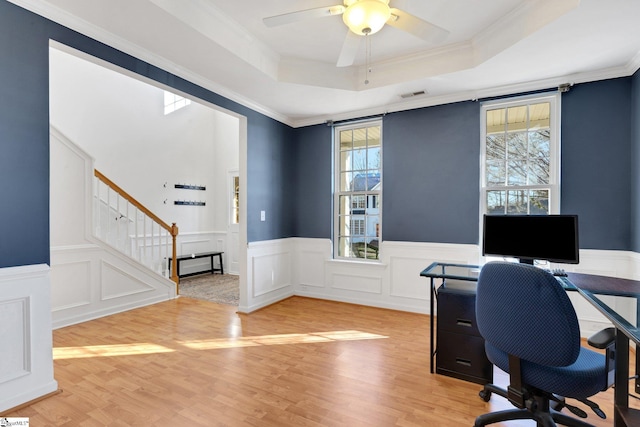 office with crown molding, a tray ceiling, wood-type flooring, and ceiling fan