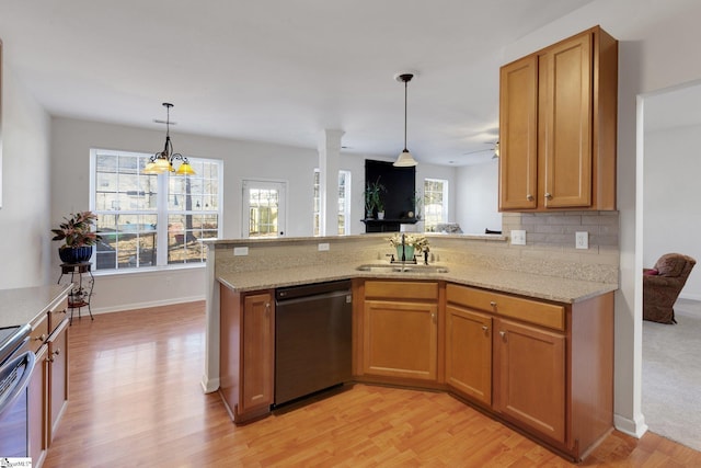 kitchen with decorative light fixtures, dishwasher, sink, light stone counters, and kitchen peninsula