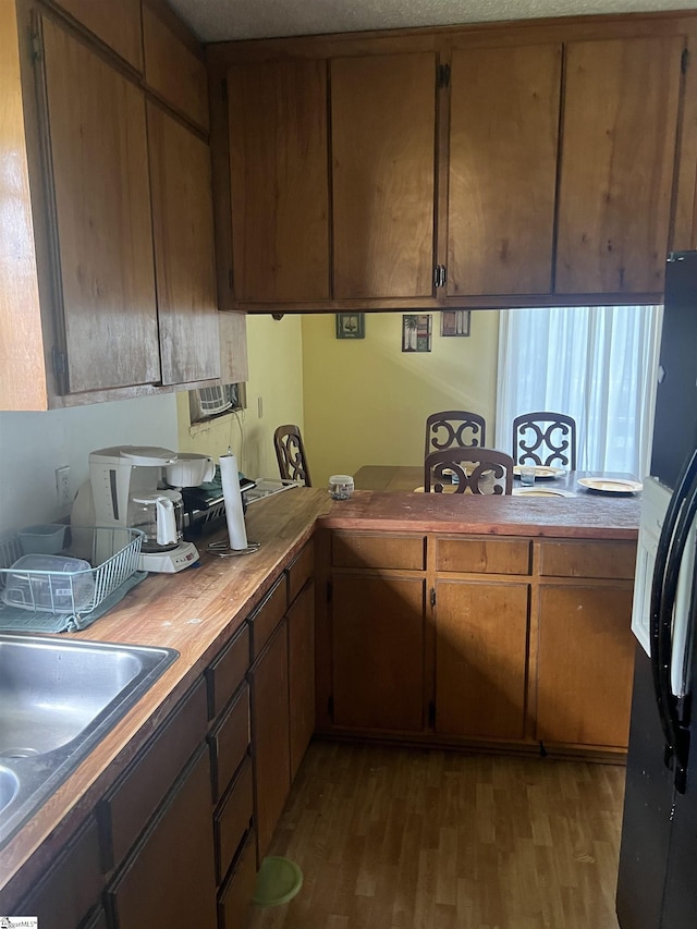 kitchen featuring sink, dark hardwood / wood-style floors, black fridge, and butcher block counters