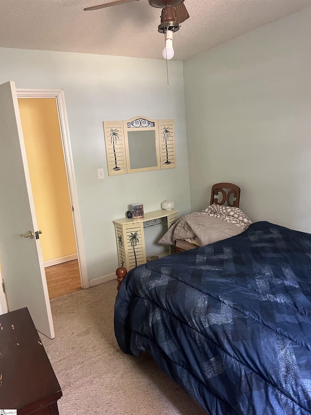 carpeted bedroom with ceiling fan and a textured ceiling