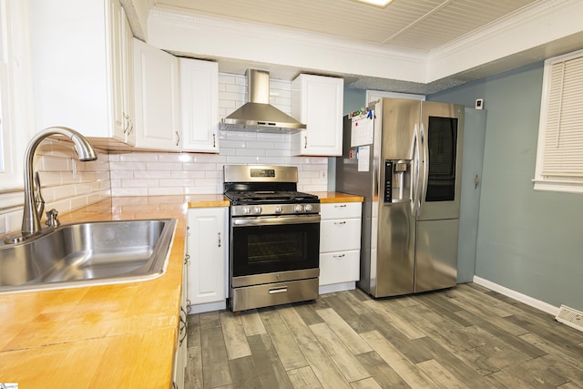 kitchen with stainless steel appliances, sink, white cabinets, and wall chimney range hood