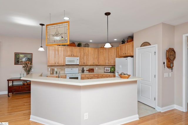 kitchen featuring tasteful backsplash, a center island with sink, white appliances, hanging light fixtures, and light wood-type flooring