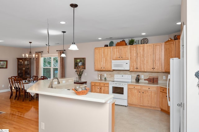 kitchen with white appliances, decorative light fixtures, backsplash, a chandelier, and a center island with sink