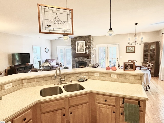 kitchen featuring light hardwood / wood-style floors, a fireplace, plenty of natural light, and sink