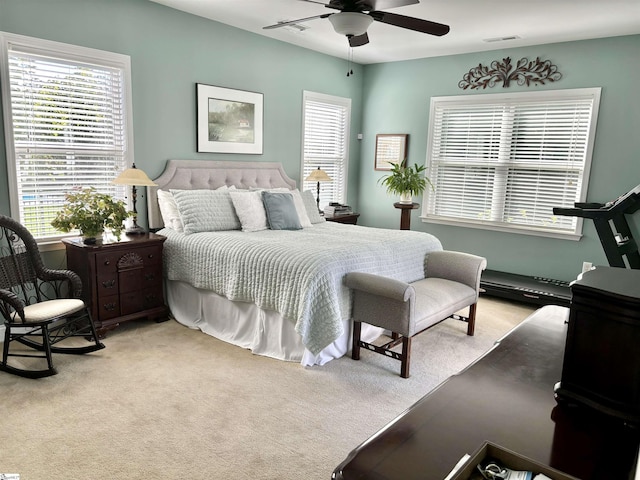 carpeted bedroom with ceiling fan and multiple windows