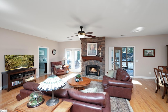 living room with ceiling fan, a fireplace, and light hardwood / wood-style flooring