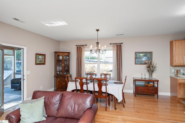 dining space featuring light wood-type flooring and an inviting chandelier