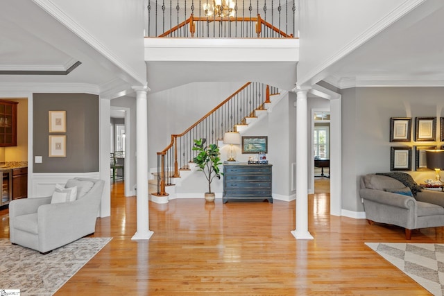 entrance foyer with wine cooler, ornamental molding, decorative columns, and hardwood / wood-style floors