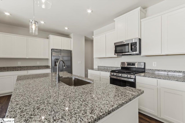 kitchen with stainless steel appliances, sink, white cabinets, and a kitchen island with sink