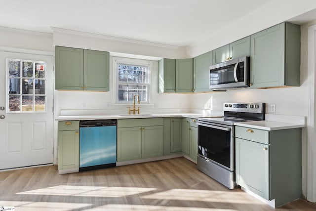 kitchen with light wood-type flooring, appliances with stainless steel finishes, sink, and green cabinets