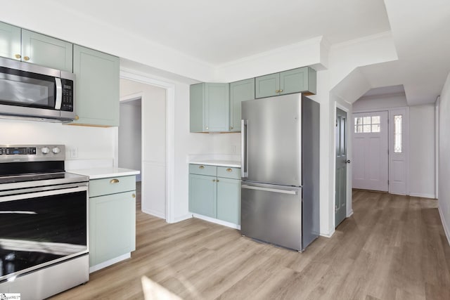 kitchen with appliances with stainless steel finishes, light hardwood / wood-style flooring, crown molding, and green cabinetry