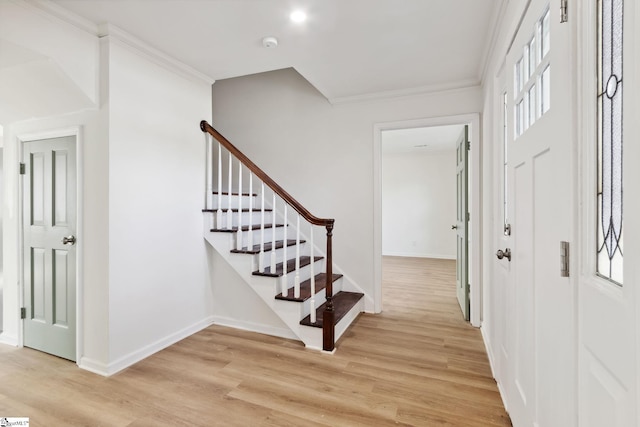 entrance foyer with ornamental molding and light hardwood / wood-style floors