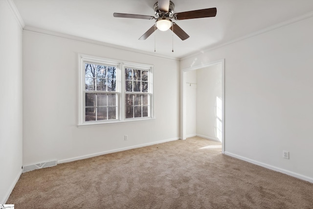 spare room featuring ceiling fan, light colored carpet, and crown molding