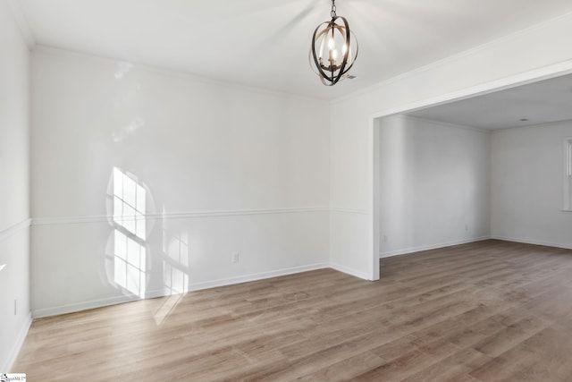 empty room with ornamental molding, a chandelier, and hardwood / wood-style floors