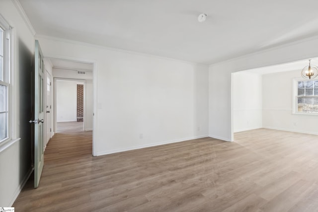 spare room with crown molding, a chandelier, and light wood-type flooring