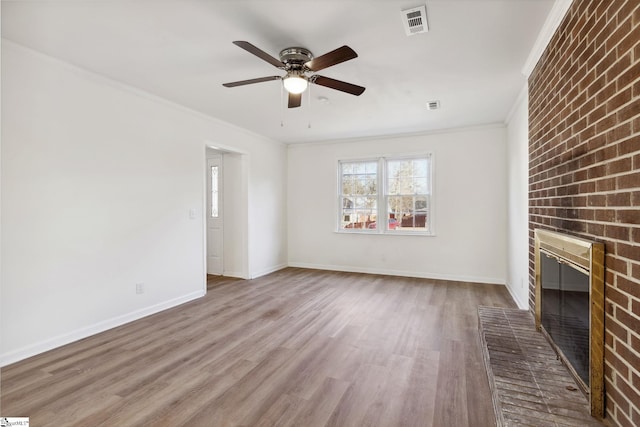 unfurnished living room featuring ceiling fan, a brick fireplace, crown molding, and hardwood / wood-style floors