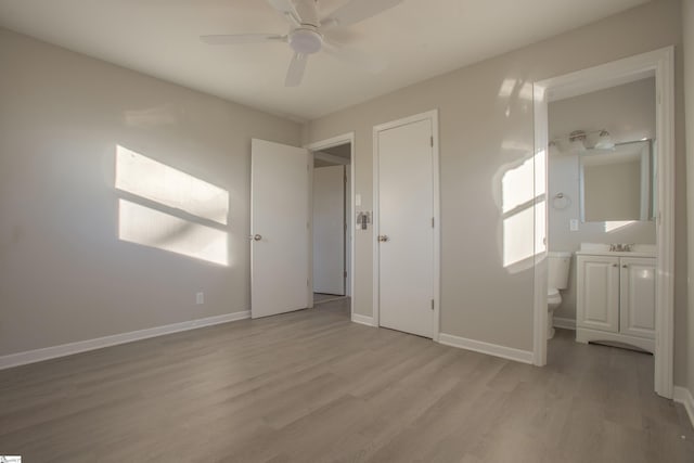 unfurnished bedroom featuring ceiling fan, ensuite bath, and light wood-type flooring