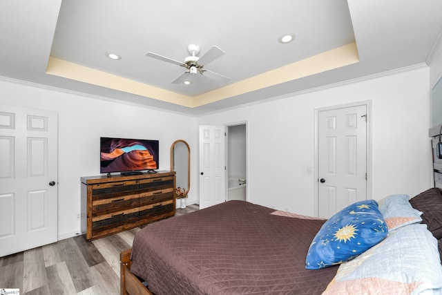 bedroom featuring ceiling fan, wood-type flooring, a tray ceiling, and crown molding