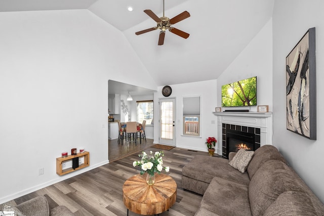 living room featuring ceiling fan, a fireplace, wood-type flooring, and high vaulted ceiling