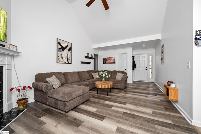 living room featuring high vaulted ceiling, dark wood-type flooring, ceiling fan, and a fireplace