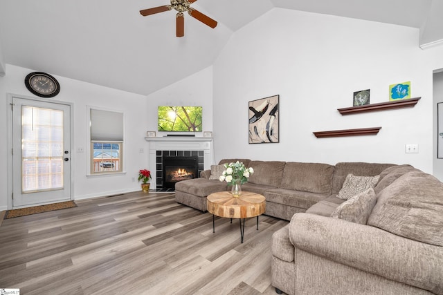 living room featuring ceiling fan, hardwood / wood-style floors, lofted ceiling, and a fireplace