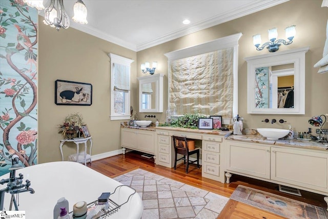 bathroom with vanity, hardwood / wood-style floors, a bathing tub, an inviting chandelier, and ornamental molding