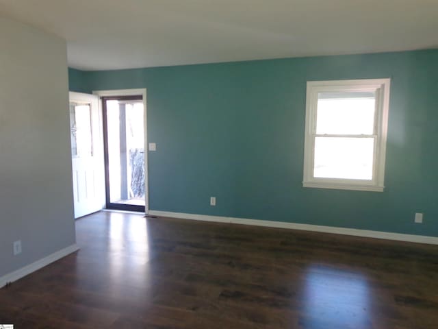 spare room with dark wood-type flooring and a wealth of natural light