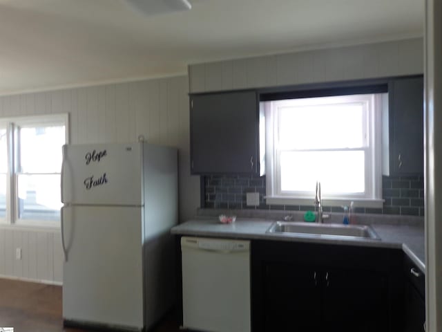 kitchen featuring sink, wood walls, and white appliances