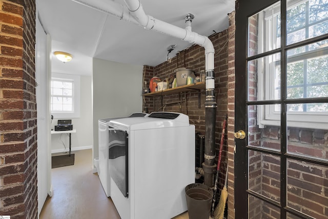 laundry area with brick wall and washing machine and clothes dryer