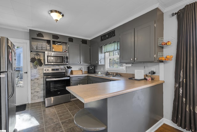 kitchen with stainless steel appliances, sink, kitchen peninsula, gray cabinetry, and a breakfast bar area