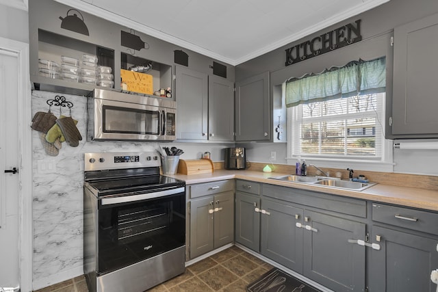 kitchen with appliances with stainless steel finishes, sink, gray cabinetry, and ornamental molding