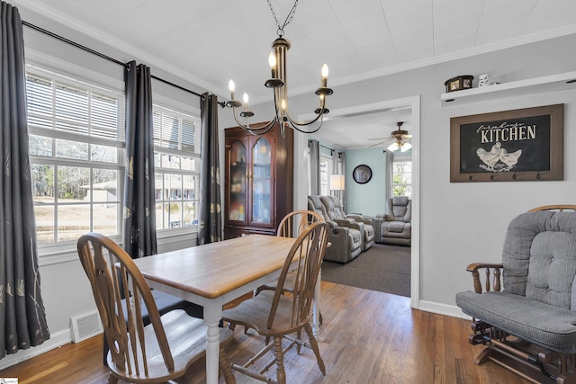 dining area featuring ceiling fan with notable chandelier, dark hardwood / wood-style flooring, and crown molding