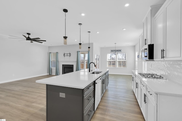 kitchen featuring white cabinetry, pendant lighting, appliances with stainless steel finishes, and a center island with sink