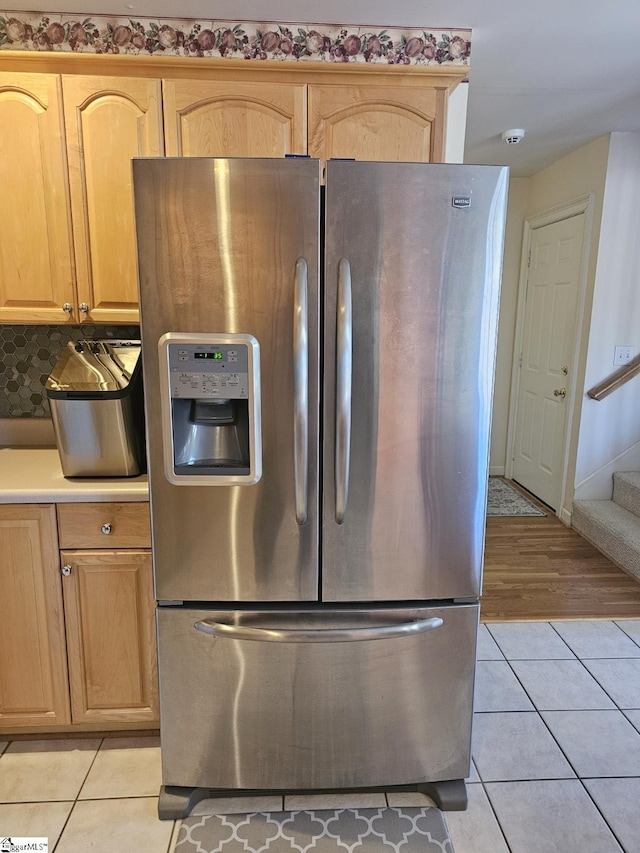 kitchen with stainless steel fridge, light brown cabinetry, and light tile patterned floors