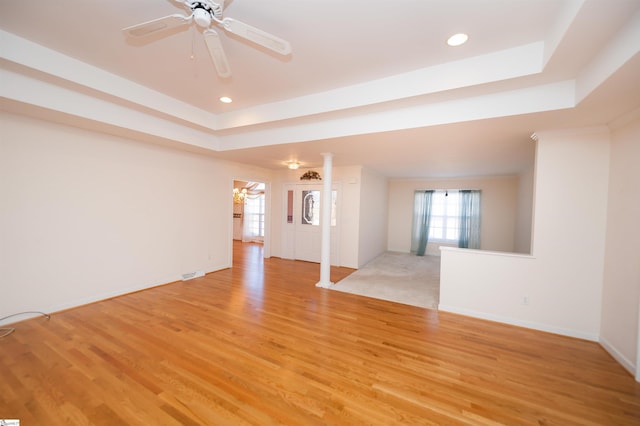 interior space featuring a tray ceiling, ceiling fan, and light wood-type flooring