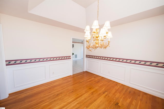 empty room featuring hardwood / wood-style flooring and a notable chandelier