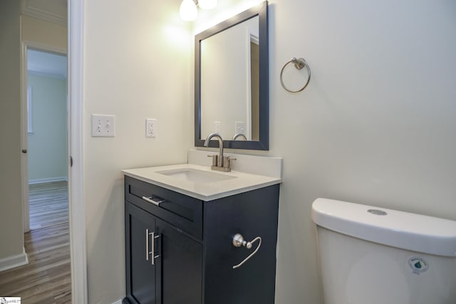 bathroom with toilet, vanity, crown molding, and hardwood / wood-style floors