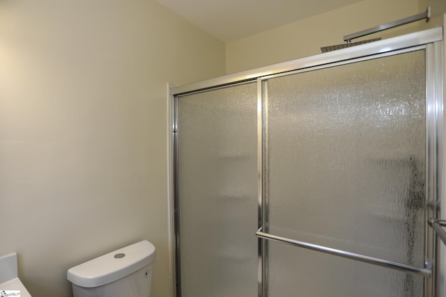 bathroom featuring toilet and a shower with shower door