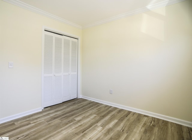 unfurnished bedroom featuring light wood-type flooring, a closet, and ornamental molding